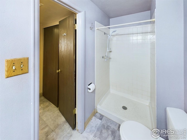 bathroom with a tile shower and toilet