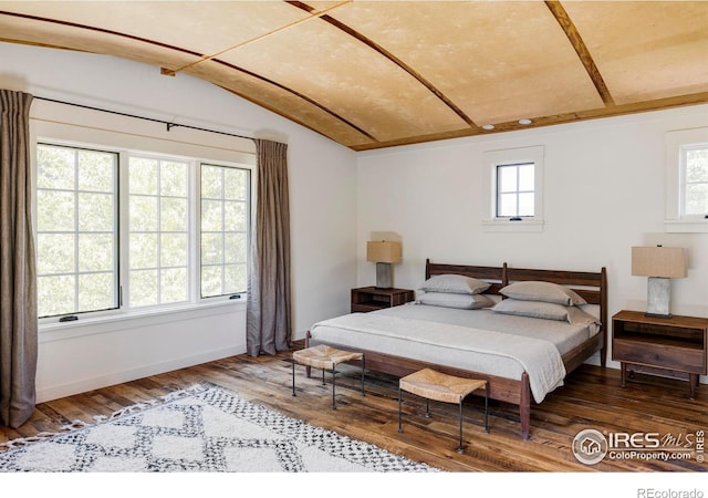 bedroom with vaulted ceiling, multiple windows, and hardwood / wood-style flooring