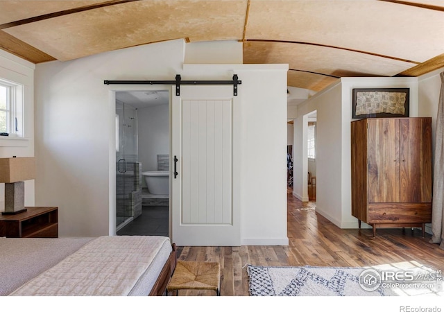 bedroom with vaulted ceiling, ensuite bathroom, hardwood / wood-style floors, and a barn door