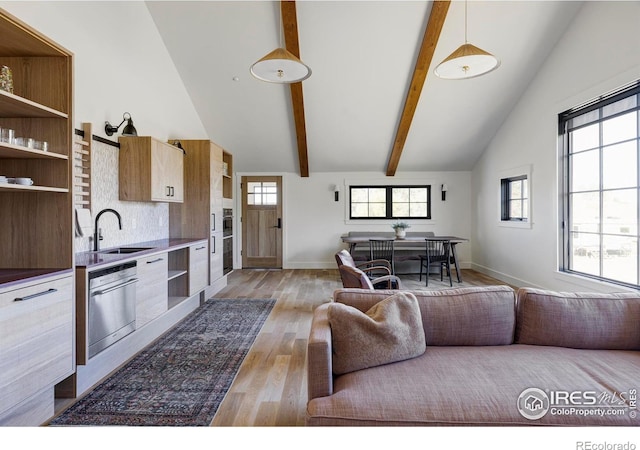 living room featuring high vaulted ceiling, light wood-type flooring, beam ceiling, and sink