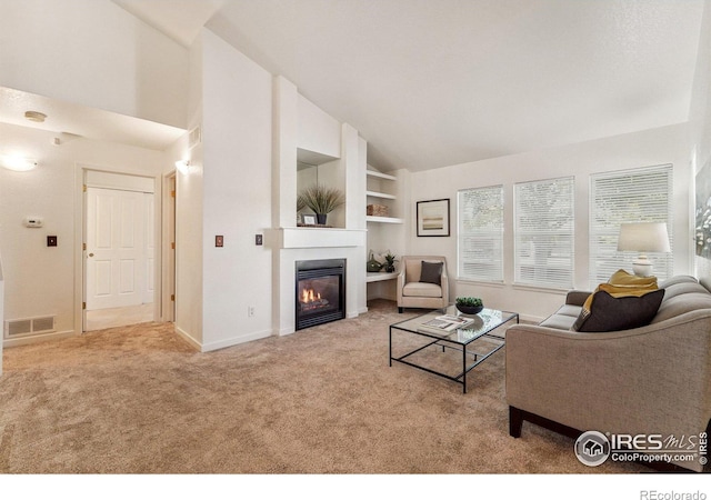 carpeted living room with built in shelves and high vaulted ceiling