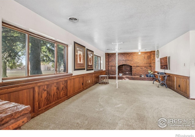 interior space featuring a brick fireplace, a textured ceiling, brick wall, and wooden walls