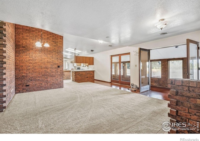 living room featuring brick wall, a textured ceiling, lofted ceiling, and a notable chandelier