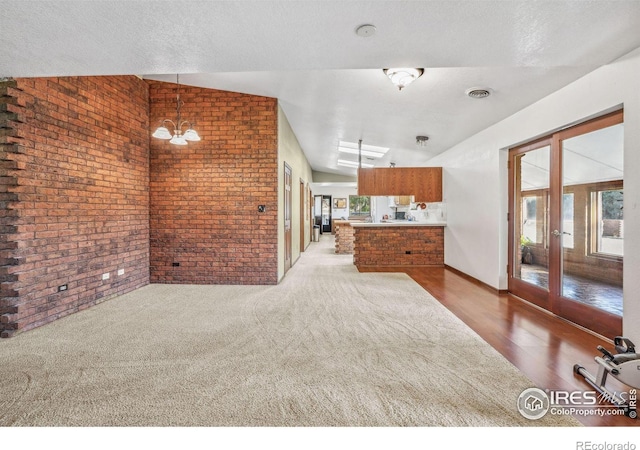 interior space featuring a wealth of natural light, lofted ceiling, wood-type flooring, and brick wall