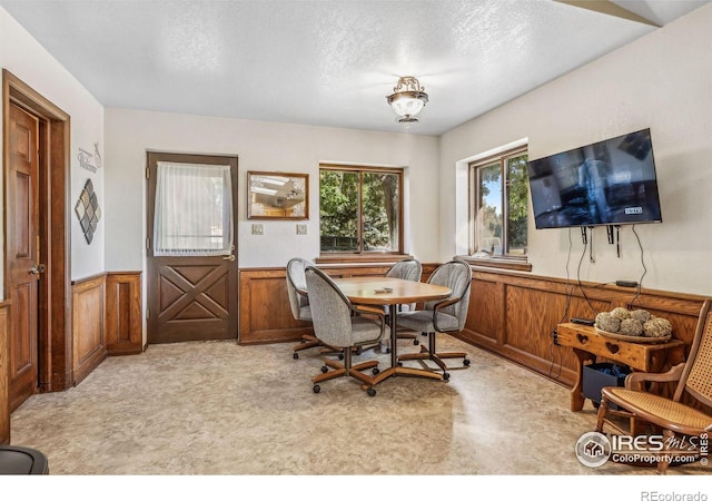 dining area with a textured ceiling and wood walls