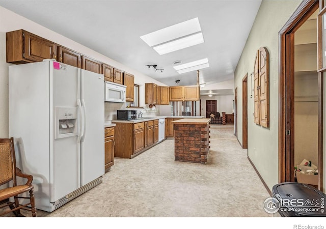 kitchen featuring lofted ceiling with skylight, white appliances, and a center island