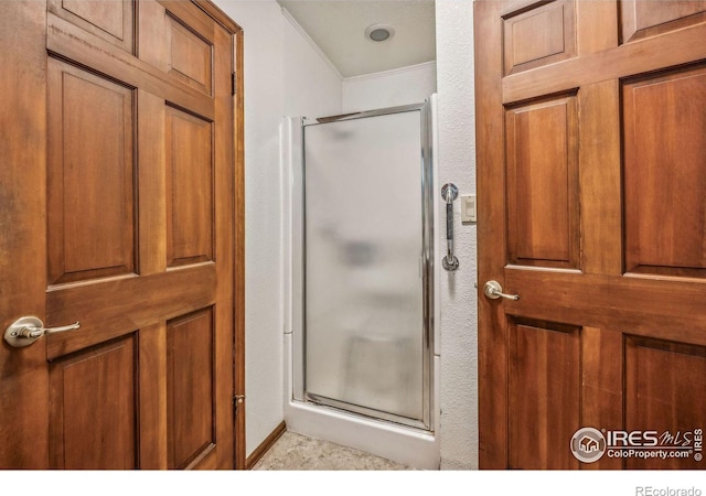 bathroom with crown molding and a shower with shower door