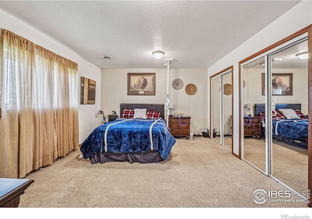 bedroom featuring multiple closets, a textured ceiling, and carpet flooring