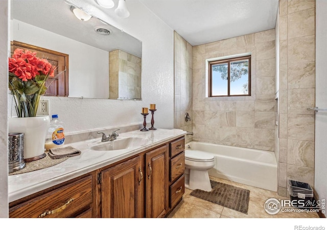 full bathroom featuring tile patterned flooring, a textured ceiling, vanity, tiled shower / bath, and toilet