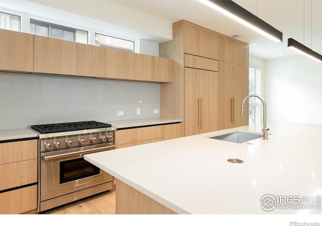 kitchen featuring light brown cabinetry, sink, and high end appliances