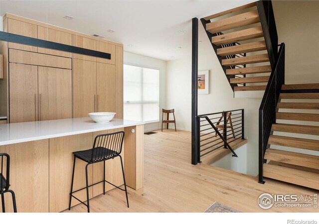 kitchen with light hardwood / wood-style flooring, light brown cabinetry, and a breakfast bar area