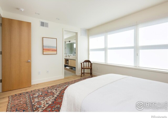 bedroom featuring light hardwood / wood-style flooring and connected bathroom