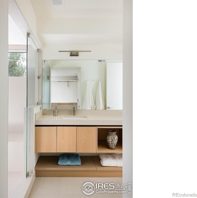 bathroom featuring tile patterned flooring, vanity, and a shower with shower door