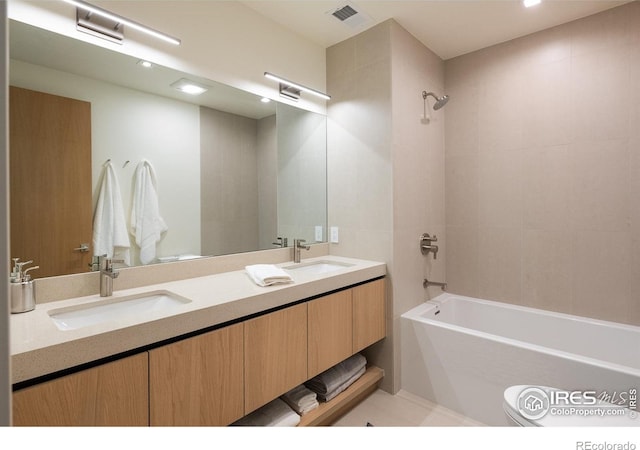 full bathroom with tiled shower / bath, vanity, and toilet