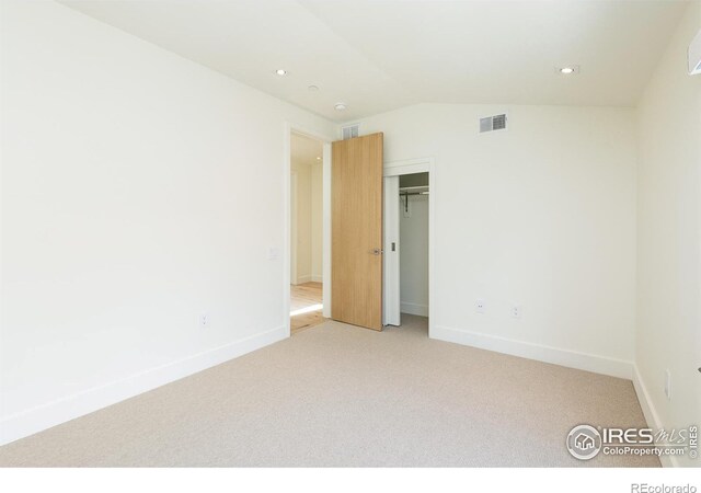 carpeted empty room featuring vaulted ceiling