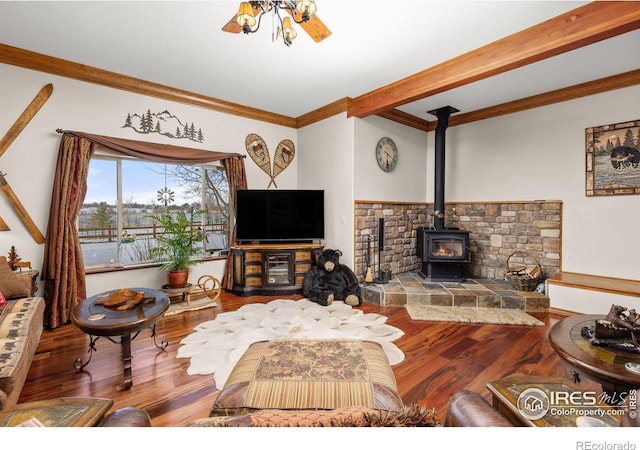 living area with a wood stove, ornamental molding, wood finished floors, and beamed ceiling