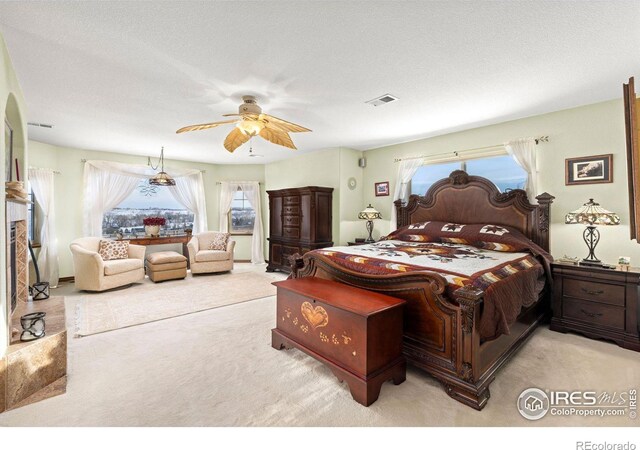 bedroom with a ceiling fan, visible vents, light carpet, and a textured ceiling