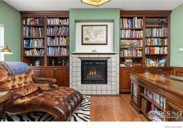 living area with light wood finished floors, a fireplace, and built in features