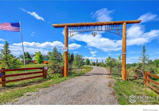 view of street featuring a gate, a gated entry, and gravel driveway