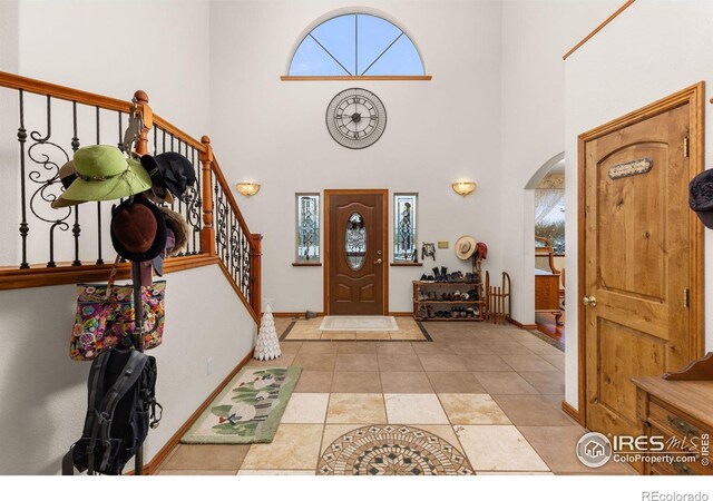 entryway featuring arched walkways, baseboards, stairway, and a towering ceiling