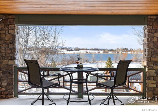 snow covered patio featuring a water view