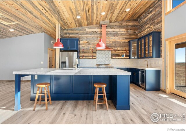 kitchen featuring pendant lighting, wood ceiling, light hardwood / wood-style floors, appliances with stainless steel finishes, and blue cabinetry