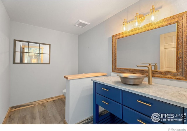 bathroom with vanity, hardwood / wood-style floors, and toilet