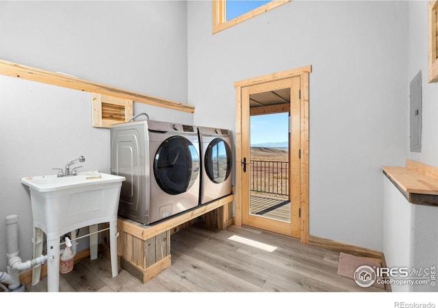 washroom featuring a wealth of natural light, light hardwood / wood-style floors, electric panel, and washer and clothes dryer