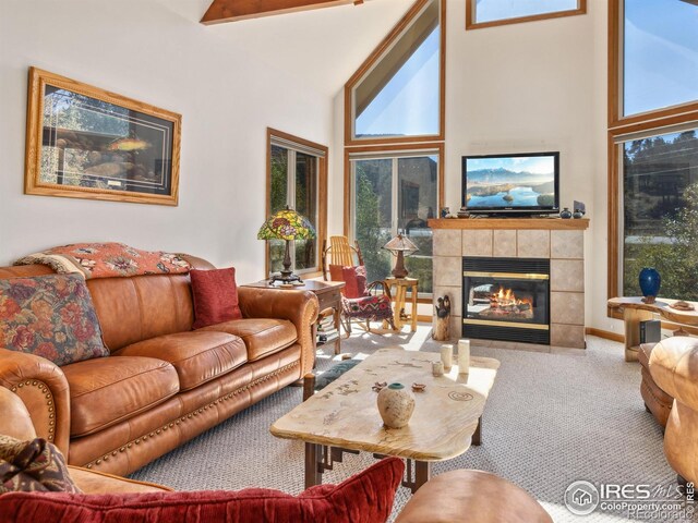 living area featuring carpet flooring, beamed ceiling, a fireplace, and high vaulted ceiling