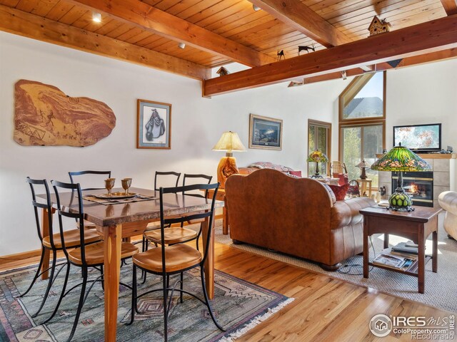 dining space with a tiled fireplace, wood ceiling, vaulted ceiling with beams, and wood finished floors