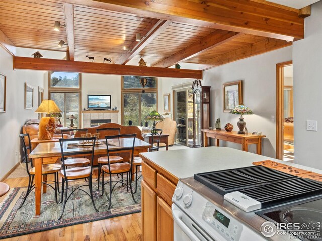 kitchen with electric range, beam ceiling, and a tile fireplace