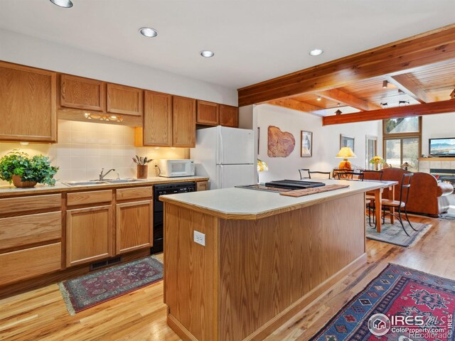 kitchen featuring white appliances, a kitchen island, light wood-style flooring, a sink, and light countertops