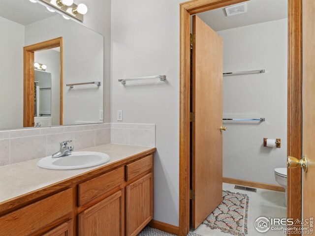 bathroom featuring vanity, toilet, tasteful backsplash, and visible vents