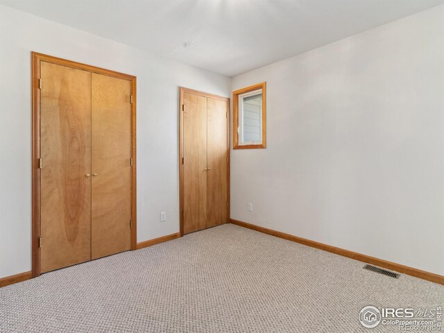 unfurnished bedroom with visible vents, light carpet, and baseboards