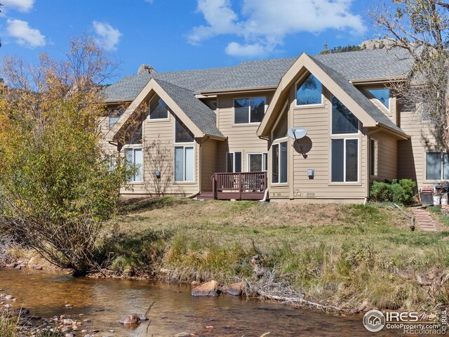 back of house featuring a deck with water view and a shingled roof