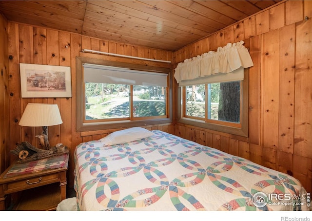 bedroom featuring wooden walls, wood ceiling, and multiple windows