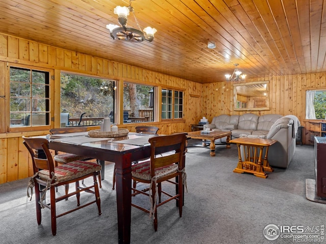 carpeted dining space featuring an inviting chandelier, wooden walls, and wooden ceiling