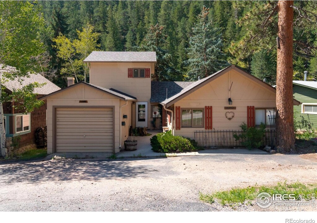 2392 W US Highway 34, Drake, CO 80515 - view of front of home with driveway, an attached garage, a shingled roof, and a forest view