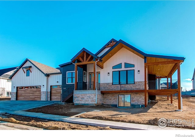 view of front of property featuring an attached garage, stone siding, and driveway