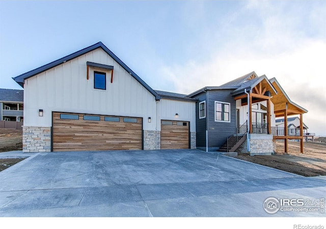 view of front of house with stone siding, board and batten siding, and concrete driveway