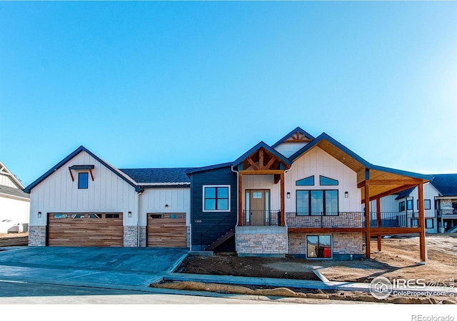 view of front of property with stone siding, concrete driveway, an attached garage, and a shingled roof