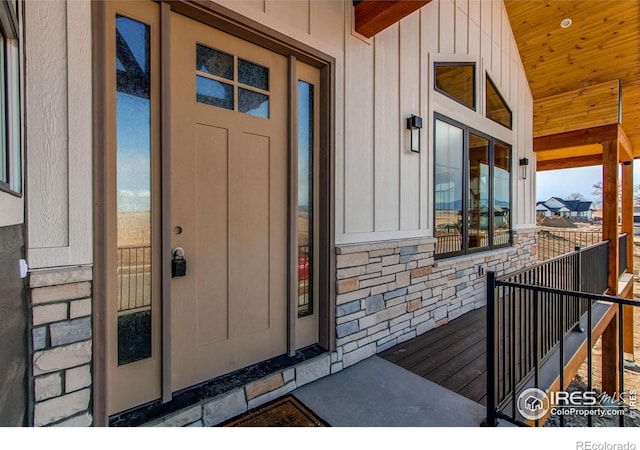 view of exterior entry featuring board and batten siding and stone siding