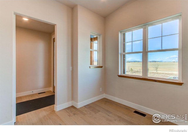 spare room featuring baseboards, visible vents, and light wood finished floors