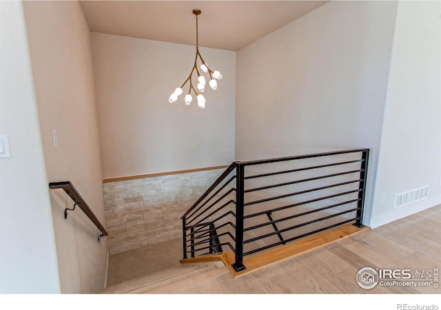 staircase with a notable chandelier and wood-type flooring