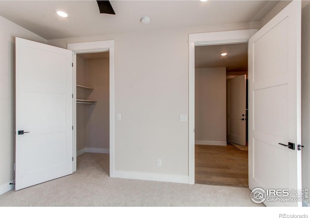 unfurnished bedroom featuring a walk in closet, recessed lighting, baseboards, and carpet floors