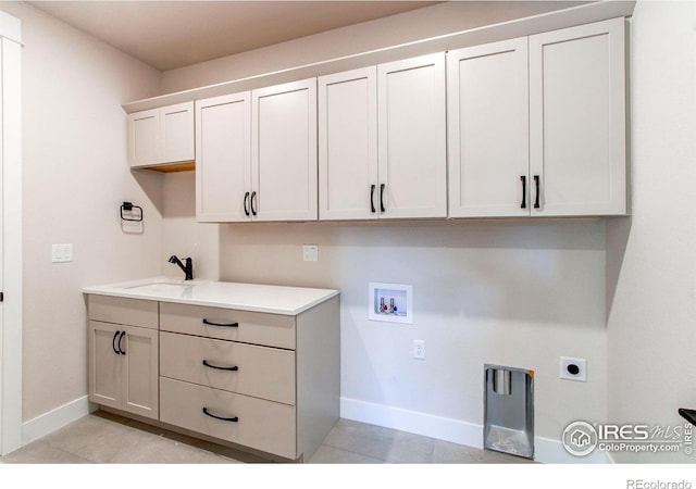 washroom with sink, cabinets, light tile patterned floors, hookup for a washing machine, and electric dryer hookup