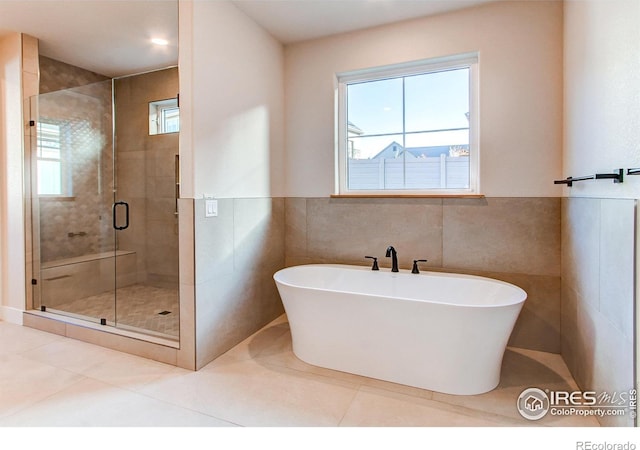 bathroom with shower with separate bathtub, tile patterned flooring, and tile walls