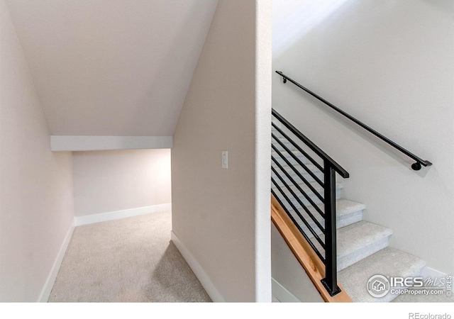 staircase with vaulted ceiling and carpet