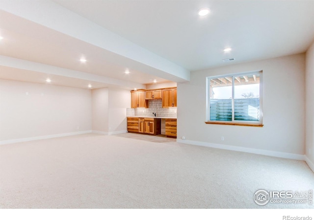 unfurnished living room featuring sink and light carpet