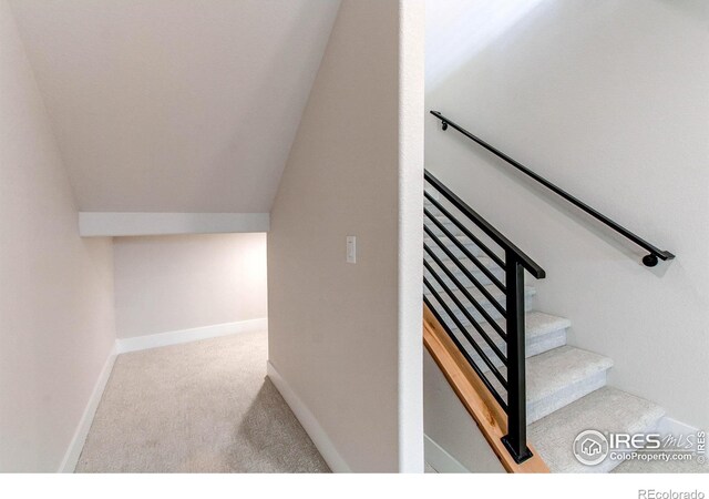 staircase featuring lofted ceiling, baseboards, and carpet floors